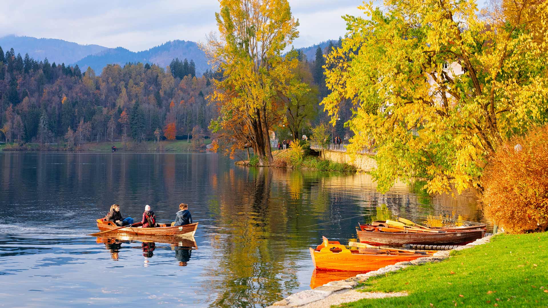 Landscape image of lake during autumn with people in a boat.